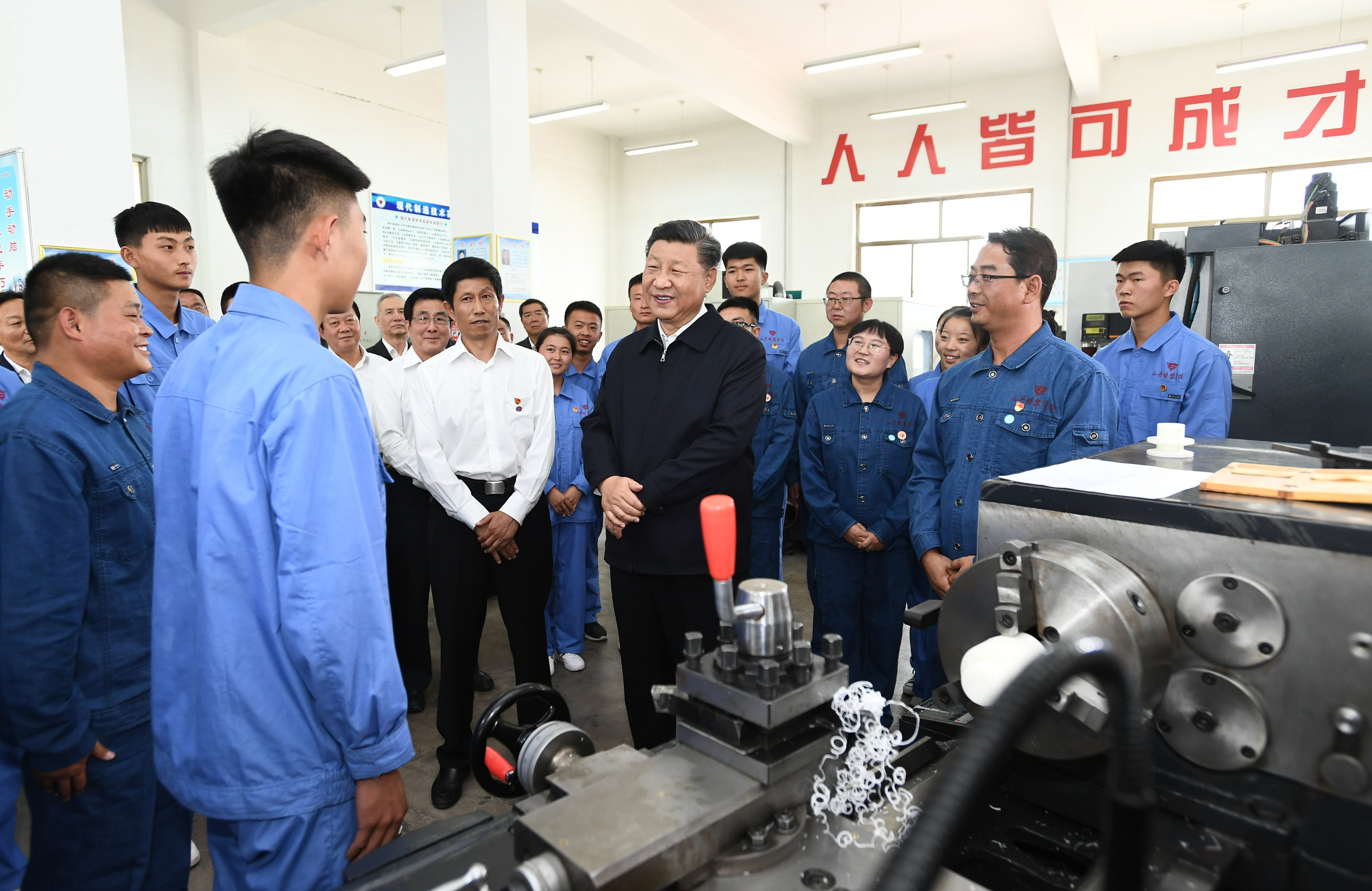 2019年8月20日,习近平在甘肃省张掖市山丹培黎学校现代制造技术实训室,观看职业技能实训,同师生亲切交流。