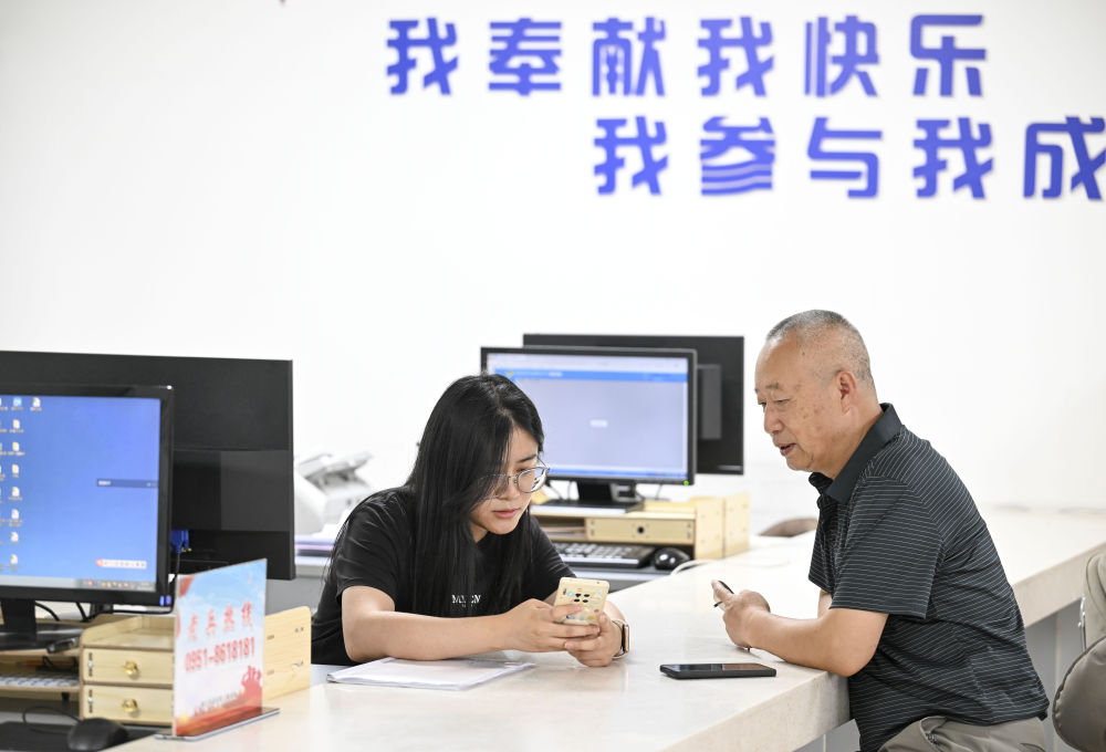 2024年6月20日,在宁夏银川市金凤区长城花园社区党群服务中心,工作人员帮助居民办理业务。图片来源 新华社