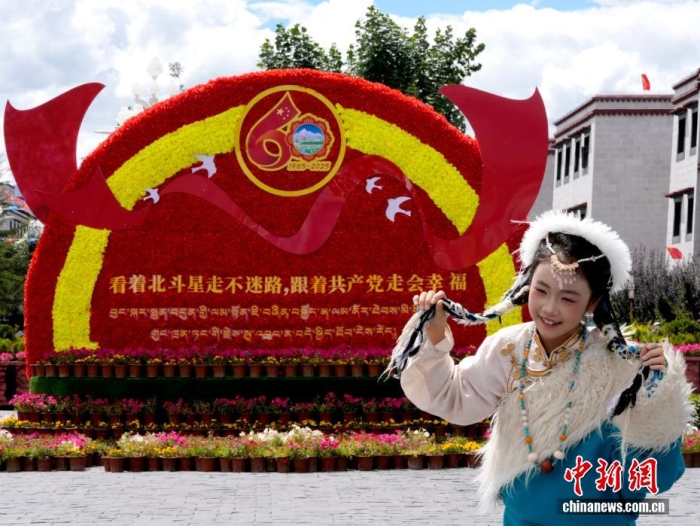 8月19日，随着西藏自治区成立60周年庆祝活动临近，拉萨氛围浓。拉萨街头，处处是张灯结彩的盛景，洋溢着一派祥和与欢腾的氛围。图为游客在拉萨大昭寺广场上的大庆宣传标语前留念。a  href='/'中新社/a记者 李林 摄